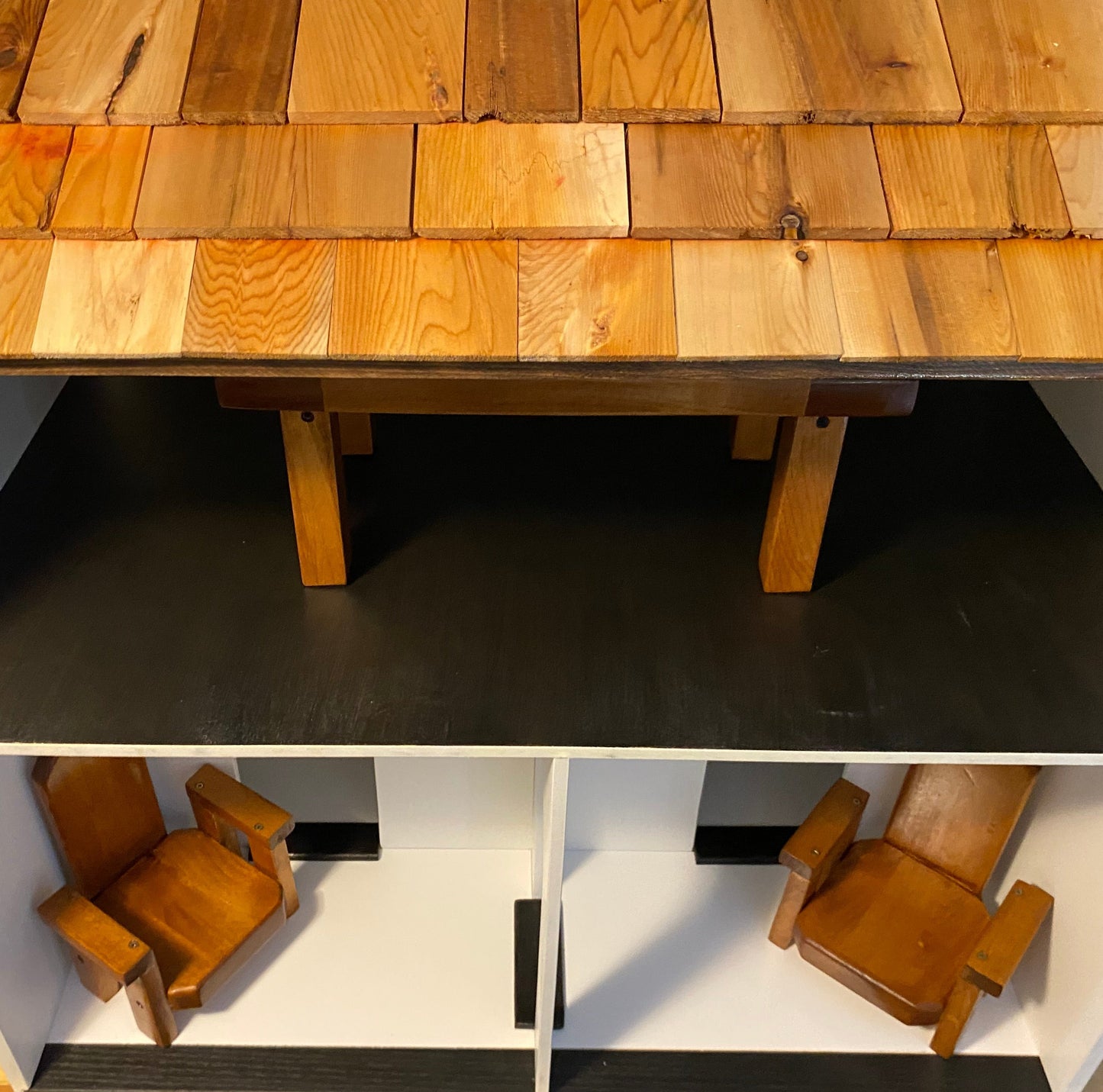 Wooden doll house with a roof and two stories and table